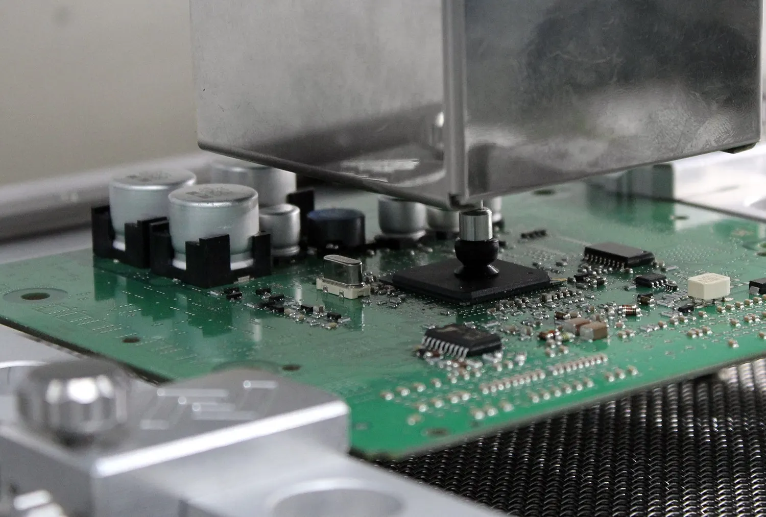 Hot-air rework nozzle lowered onto a chip on a circuit board held in a bench fixture